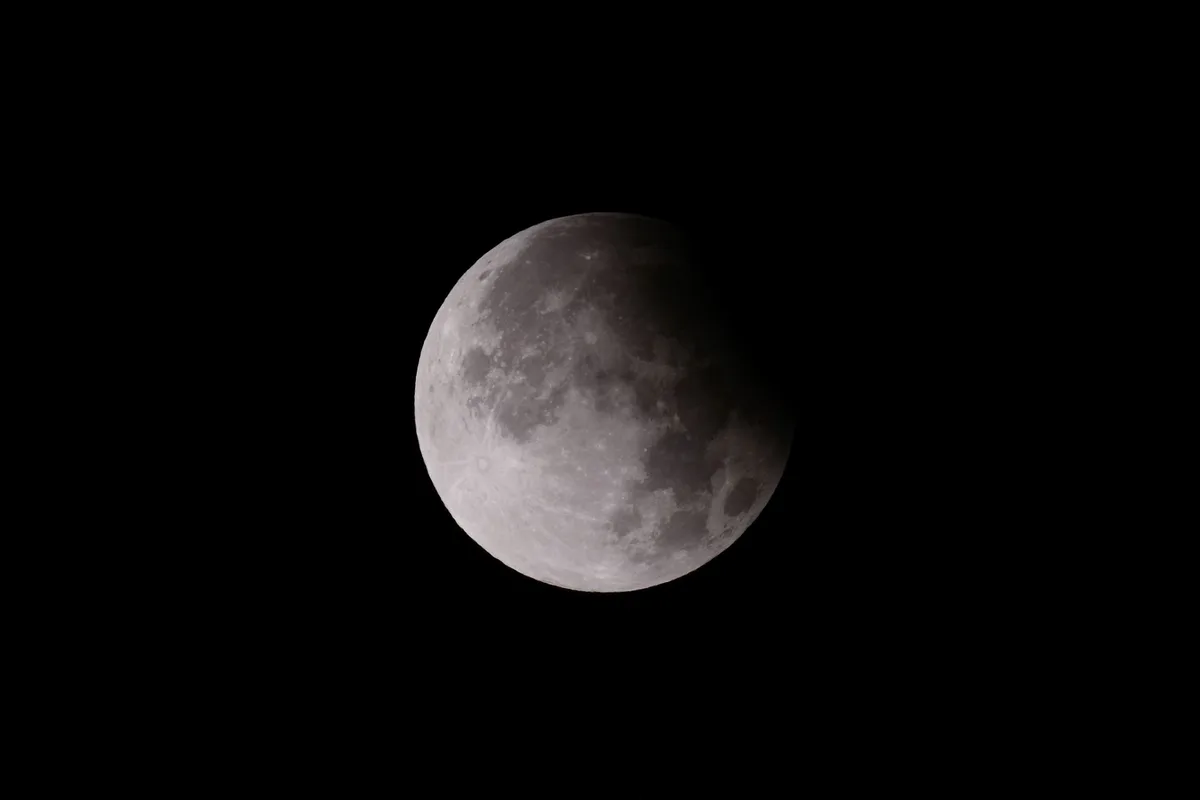 Close-up shot of a lunar eclipse, showcasing the moon's surface with shadow play.