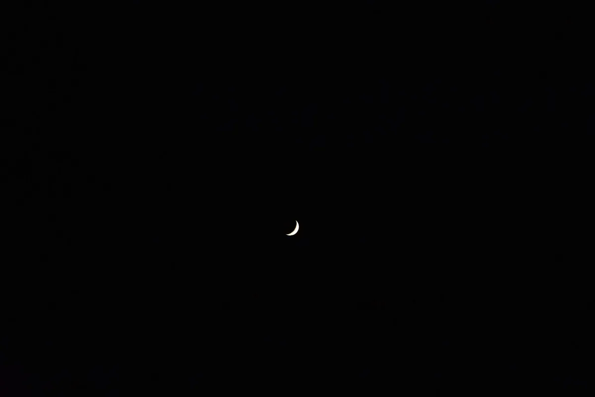 A serene crescent moon floating in a vast and dark night sky, creating a peaceful celestial scene.