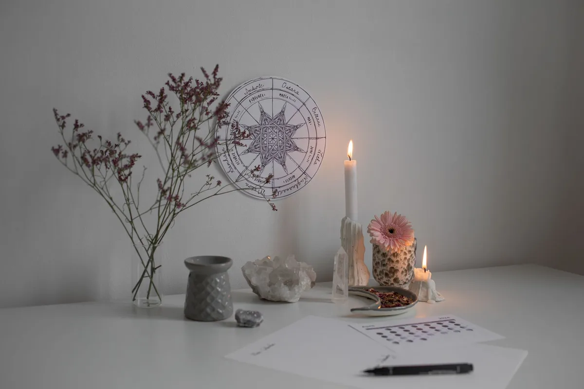 A serene desk setup with candles, crystals, and a wheel of the year decoration.