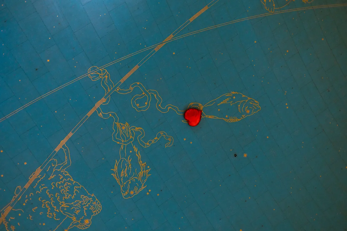 Red heart balloon against the zodiac ceiling of Grand Central Terminal, New York.
