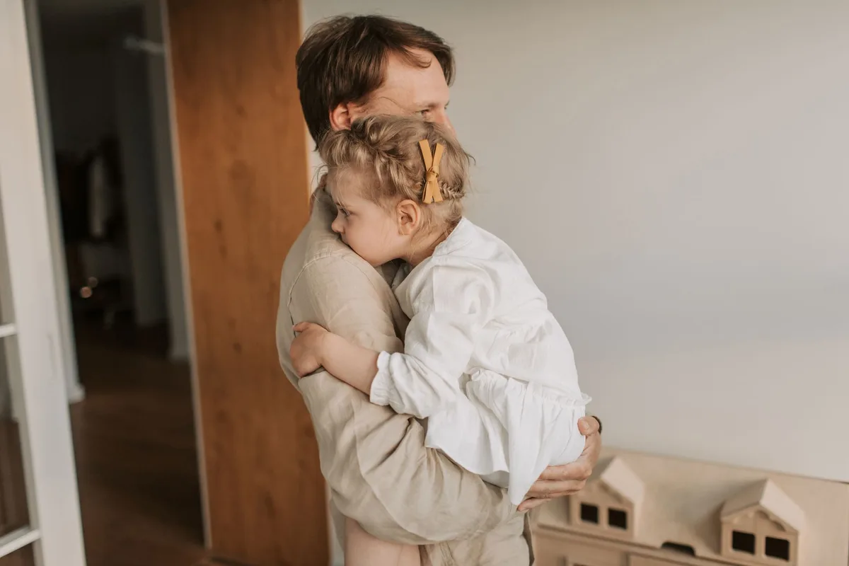 A father lovingly embraces his young daughter, showcasing tender family affection.