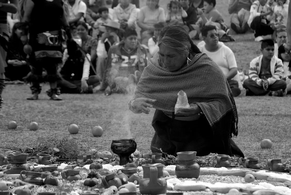 An indigenous woman performs a ritual with an audience watching closely in Mexico.